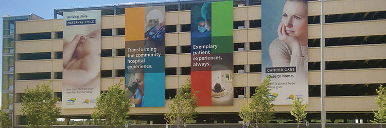 huge printed banner signs on car parking garage, full colour images on side of building