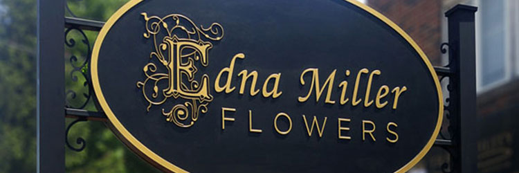 Black carved sign with carved intricate gold letters, Edna Miller Flowers, Hung between 2 posts